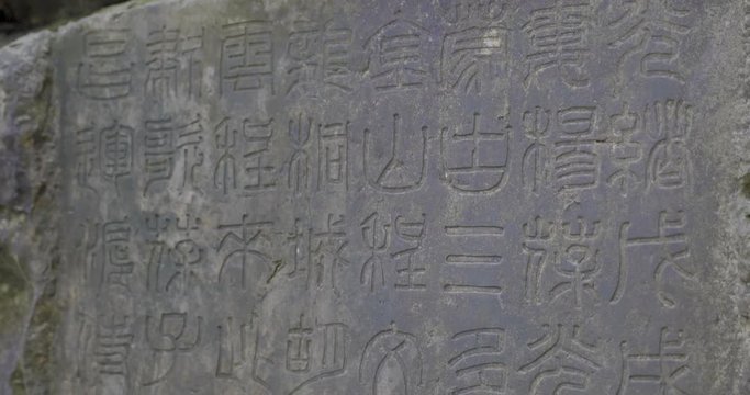 Beautiful ancient Chinese characters edged into the stone on the side of a mountain.