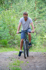 Obraz premium athlete on a bike in a coniferous forest.Healthy lifestyle.Walking by bike 