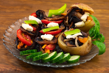 Vegetable dish with mushrooms – baked potatoes, fried mushrooms with onions and carrots, baked eggplant, fresh cucumbers, bitter pepper and basil leaves.