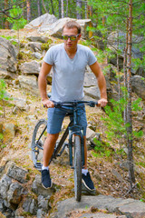 Naklejka premium athlete on a bike among the rocky terrain.Healthy lifestyle.Walking by bike