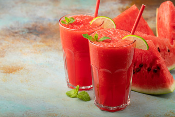 Watermelon slushie with lime, summer refreshing drink in tall glasses on a blue rusty background. with copy space
