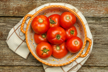 Fresh harvested tomatoes in a bowl on the wooden table. Healthy organic nutrition concept. 
