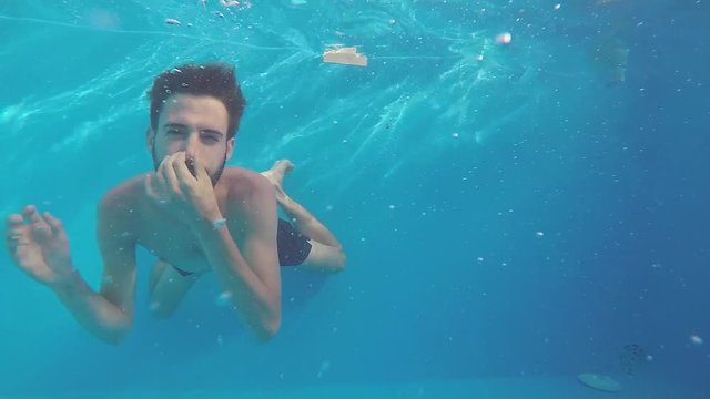 Attractive young man playing in a pool in summer