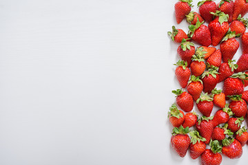 strawberry fruits on the right side on wooden background with copy space. View from above.