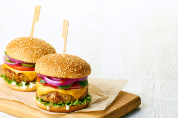 Two delicious cheeseburgers on wooden cutting board