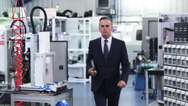 Slow Motion Portrait Of Business Owner In Factory Walking Towards Camera