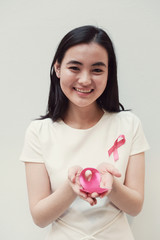 Asian young woman holding pink ribbon, breast cancer awareness, October pink concept
