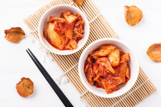 Kimchi cabbage in a bowl with chopsticks, top view, Korean food