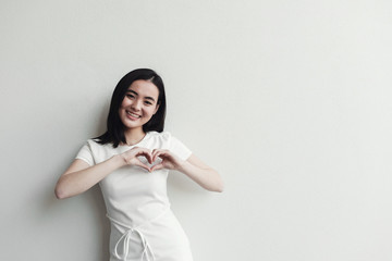 Happy Asian young woman making her hands in heart shape