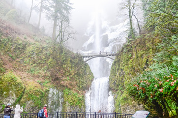 Crowded of visitor at the main lookout of the base of Multnomah Falls in winter time. A waterfall on the Oregon side of the Columbia River Gorge, along the Historic Columbia River Highway