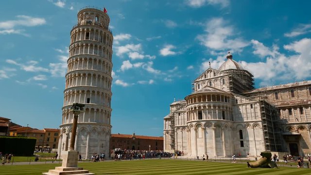 Wide tracking shot of the Leaning Tower of Pisa and Pisa Cathedral in Piazza dei Miracoli, Italy, featuring the famous bell tower. Pisa has more than 20 historic churches and several medieval palaces