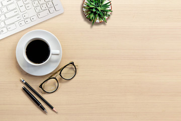 Top view of Office desk with keyboard, hot coffee, plant, vintage eyeglasses on top view and copy space. Business desk minimal style concept with copy space.