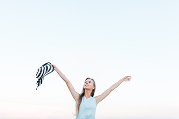 The girl was resting his hands up on the background of blue sky, concept of freedom, rest on fresh air