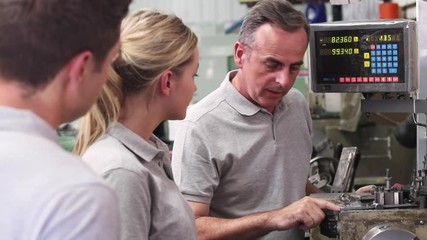 Engineer Teaching Apprentices To Use Lathe In Factory