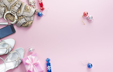 Christmas background pink Flat Lay fashion accessories handbag sandals phone gift box bow balls.