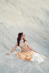 Young beautiful Caucasian woman belly dancer posing in desert