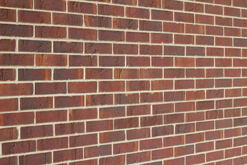 Traditional running bond pattern brown brick wall background with rust color striations (angle view)