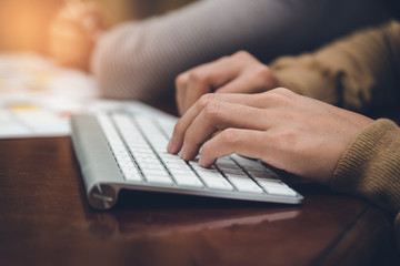A desk in an office with a laptop she is writing a blog. Women's hands on the keyboard.