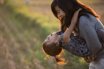 mom and kid hugging under the sunset sky