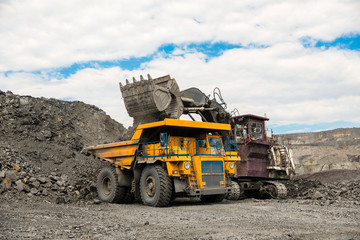 Large quarry dump truck. Loading the rock in dumper. Loading coal into body truck. Production useful minerals. Mining truck mining machinery, to transport coal from open-pit as the coal production.