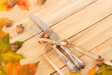 Silverware in the frame from colored maple leaves and acorns