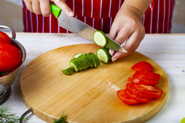 Woman  is cutting vegetables for a salad