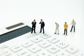 Miniature people: Businessman stand on calculator, tax, profit margins of  background. Image use...