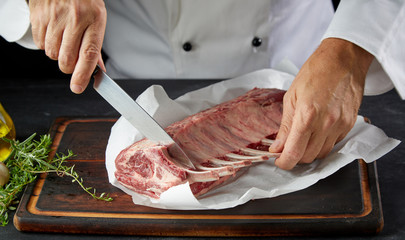 Cook wearing white coat cutting lamb chop