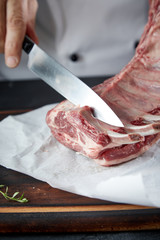 Chef or butcher cutting raw lamb chops