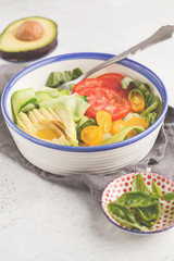 Green zucchini noodles salad with tomatoes, avocado and basil. Healthy vegan zucchini pasta.