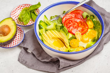 Green zucchini noodles salad with tomatoes, avocado and basil. Healthy vegan zucchini pasta.