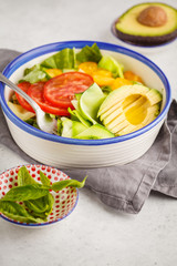 Green zucchini noodles salad with tomatoes, avocado and basil. Healthy vegan zucchini pasta.