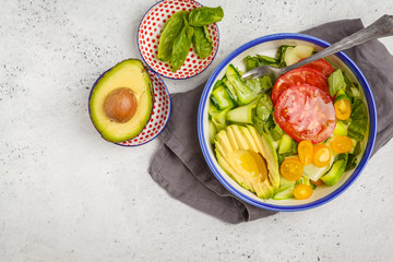 Green zucchini noodles salad with tomatoes, avocado and basil. Healthy vegan zucchini pasta.