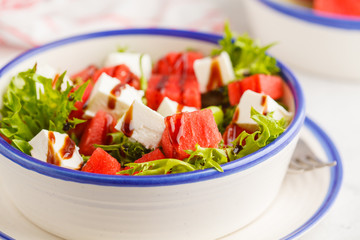 Watermelon and feta cheese salad in white plate on a white background.