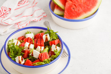 Watermelon and feta cheese salad in white plate on a white background.