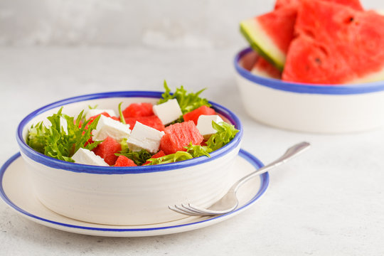 Watermelon and feta cheese salad in white plate on a white background.