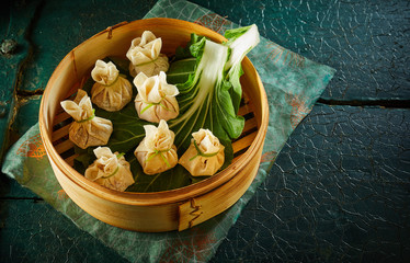 Dim sum dumplings on green leaf in bamboo basket