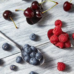 Delicious sweet berries on a spoon gray wooden background. Flat lay. Concept of vegetarian eating.