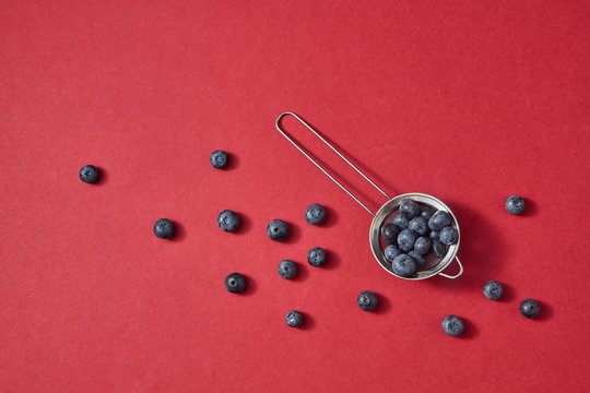 Ripe sweet blueberry in a colander a red paper background. Ntural beries pattern on a red.