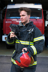 Portrait of a young fireman on the background of a fire truck