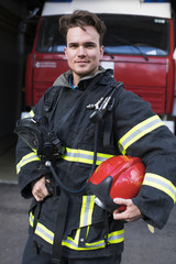 Obraz premium Portrait of a young fireman on the background of a fire truck