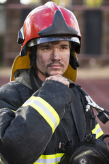 Portrait of a young fireman on the background of a fire truck