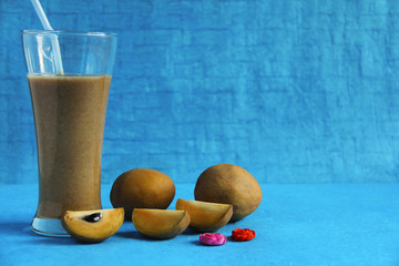 Chikoo or sapota with its juice isolated on light blue background