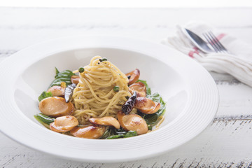 spaghetti with sausage chilli spicy on white table. yellow pasta on white dish.