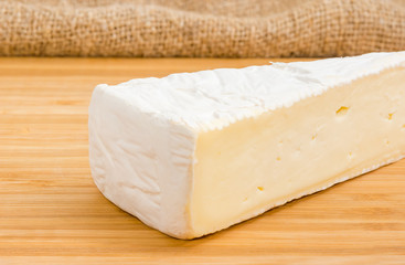 Piece of the brie cheese on a bamboo wooden surface