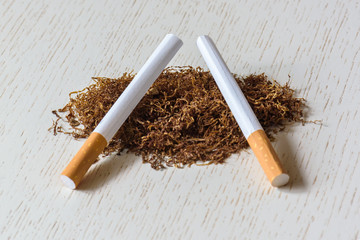 A handful of natural tobacco and empty cigarette cases on a white wooden table. Smoking. Nicotine addiction. Danger to health.