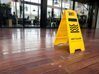 yellow plastic cone with sign showing warning of wet floor in restaurant