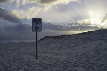 A warning sign on an Australian beach stating there is no lifeguards present.  - 215595105