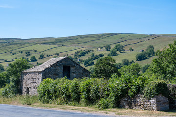 Hills of Yorkshire Dales with stone barn in foreground