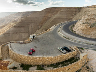 Parking lot with three cars and a simple kiosk on the King Highway just behind the Wadi Mujib Reservoir, aerial view. © Frank